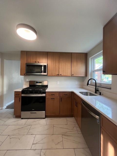 kitchen featuring light countertops, appliances with stainless steel finishes, marble finish floor, and a sink
