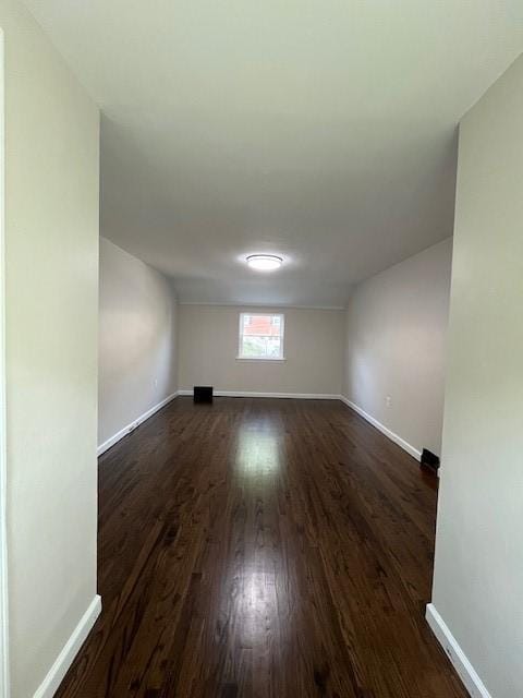 spare room featuring dark wood-style flooring and baseboards