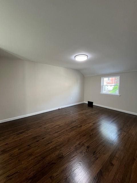 unfurnished room with baseboards and dark wood-style floors