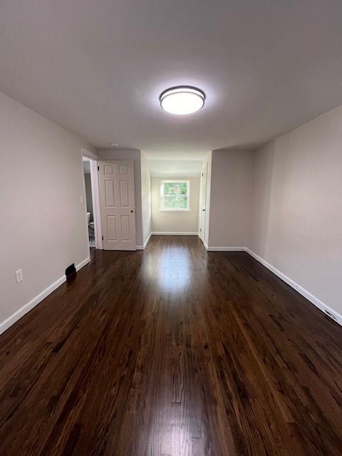 empty room with baseboards and dark wood-style floors