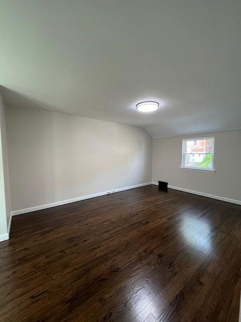 empty room featuring dark wood-style flooring and baseboards