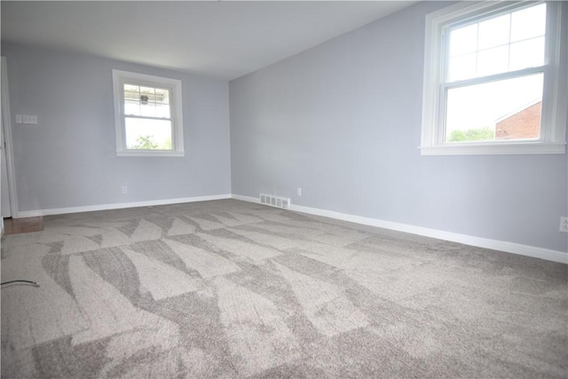 carpeted spare room featuring baseboards and visible vents