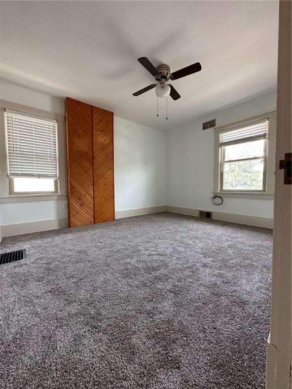 spare room with ceiling fan, carpet floors, and visible vents