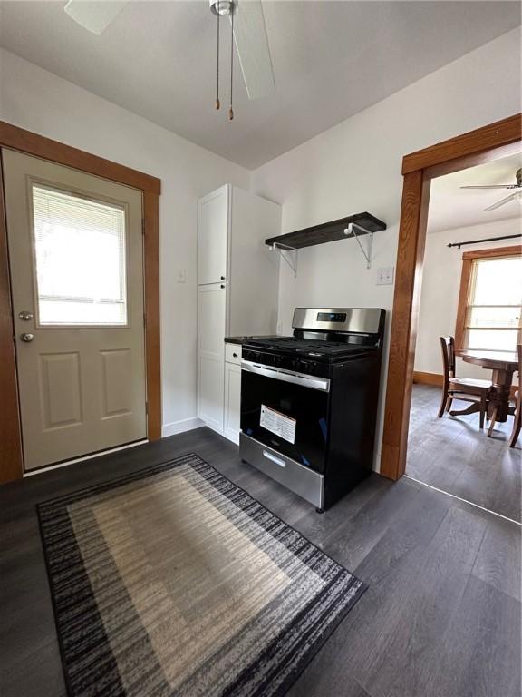 kitchen with open shelves, stainless steel gas stove, dark wood-type flooring, ceiling fan, and white cabinetry