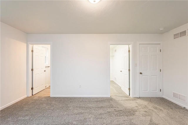 spare room with carpet, visible vents, and baseboards