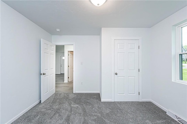 unfurnished bedroom featuring carpet, baseboards, and visible vents