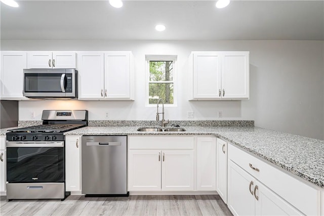 kitchen with a sink, light wood-type flooring, white cabinetry, appliances with stainless steel finishes, and recessed lighting