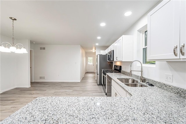 kitchen with stainless steel appliances, light wood-style flooring, visible vents, and a sink