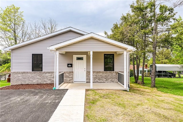 bungalow-style home featuring covered porch, brick siding, and a front lawn