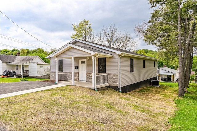 view of front of home with a front yard, a porch, and cooling unit