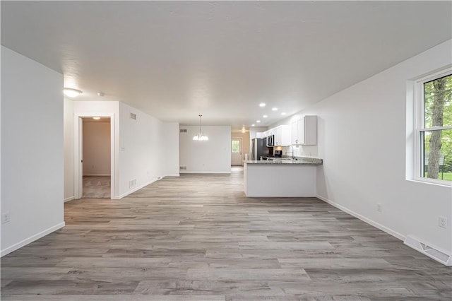 unfurnished living room with light wood-style flooring, visible vents, baseboards, a chandelier, and recessed lighting