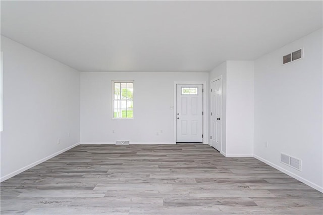 spare room featuring light wood-type flooring, baseboards, and visible vents