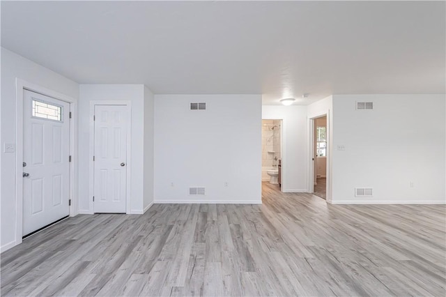 unfurnished living room with light wood-style flooring, baseboards, and visible vents