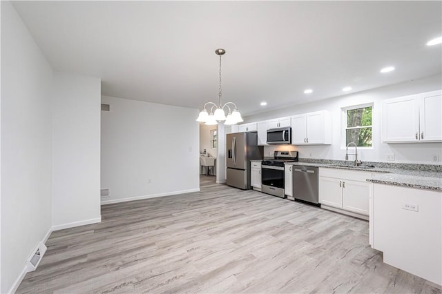 kitchen featuring light wood-style floors, stainless steel appliances, light stone counters, and a sink