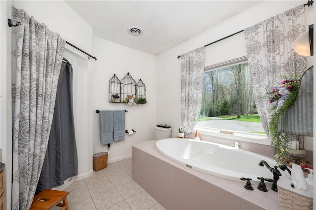 bathroom featuring baseboards, a bath, visible vents, and tile patterned floors