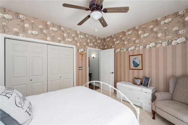 bedroom with wallpapered walls, a closet, ceiling fan, and carpet