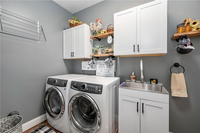 washroom with washing machine and clothes dryer, baseboards, a sink, and cabinet space