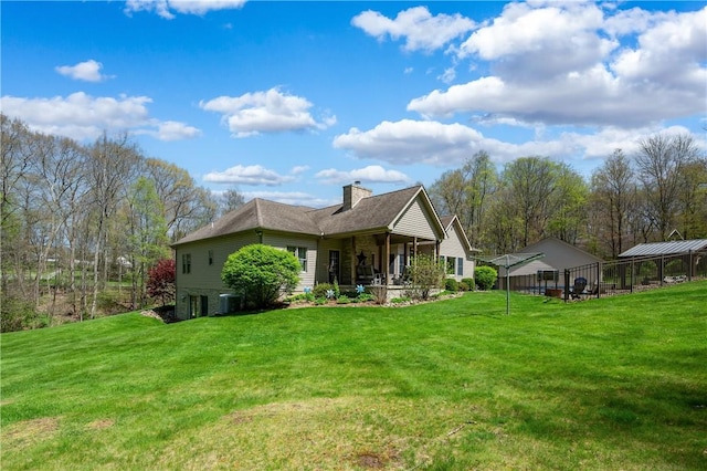 back of house featuring central AC unit, a chimney, and a lawn