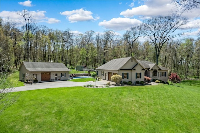 exterior space featuring a yard, driveway, a view of trees, and a pool