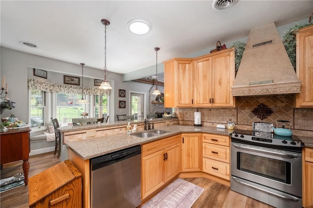 kitchen with premium range hood, light wood-style floors, stainless steel appliances, and a sink