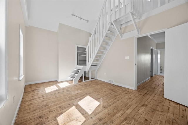 5611 Wickliff St, Lawrenceville, PA 15201 - unfurnished living room featuring stairs, wood-type flooring, a towering ceiling, and visible vents
