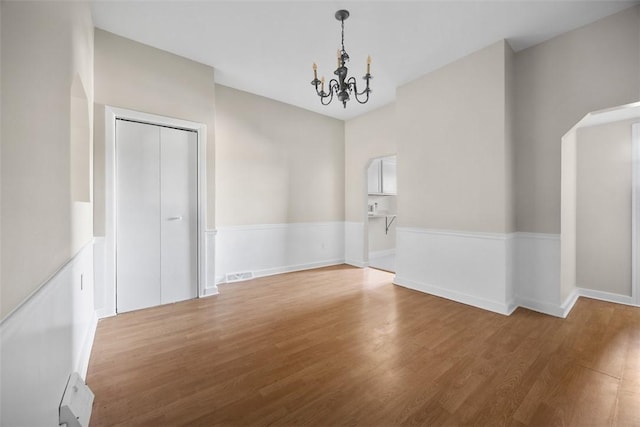 5611 Wickliff St, Lawrenceville, PA 15201 - spare room with wood finished floors, visible vents, arched walkways, a notable chandelier, and baseboards