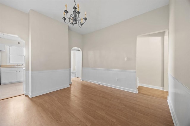 5611 Wickliff St, Lawrenceville, PA 15201 - unfurnished dining area with arched walkways, an inviting chandelier, light wood-type flooring, and a sink