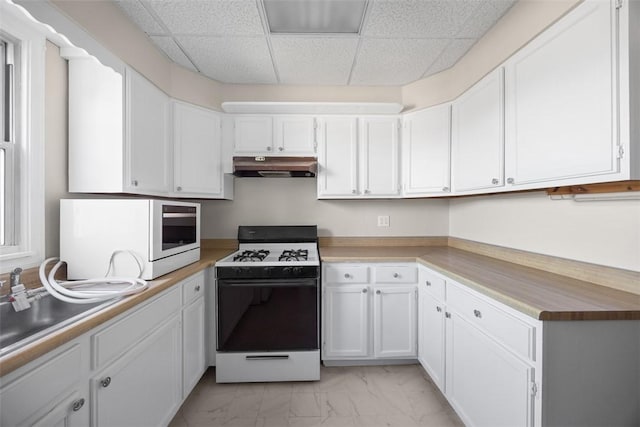 5611 Wickliff St, Lawrenceville, PA 15201 - kitchen featuring under cabinet range hood, marble finish floor, white cabinetry, gas range, and a paneled ceiling