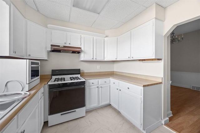 5611 Wickliff St, Lawrenceville, PA 15201 - kitchen with a drop ceiling, under cabinet range hood, white gas range oven, light countertops, and white cabinets