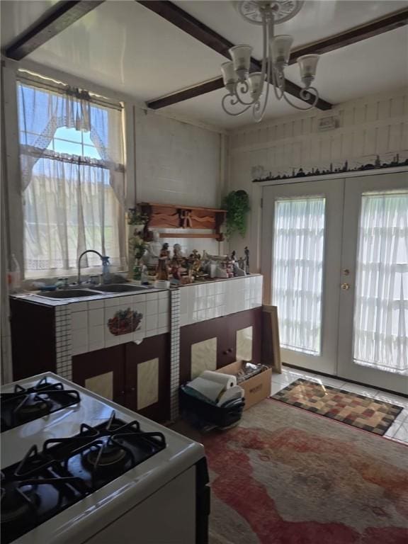kitchen with a sink, a chandelier, gas range gas stove, and french doors