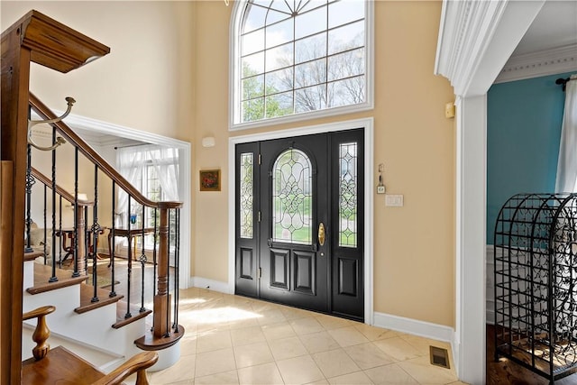 foyer featuring tile patterned flooring, a high ceiling, baseboards, and plenty of natural light