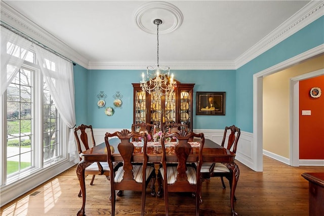 dining space with plenty of natural light, wainscoting, and a notable chandelier