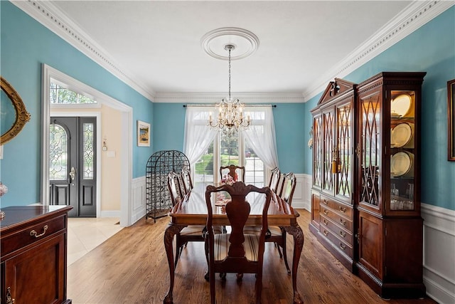 dining space featuring a chandelier, a wainscoted wall, and a healthy amount of sunlight