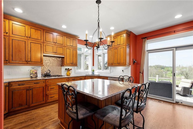 kitchen featuring light stone countertops, a notable chandelier, a center island, and wood finished floors