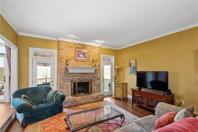 living area with crown molding, a brick fireplace, baseboards, and wood finished floors