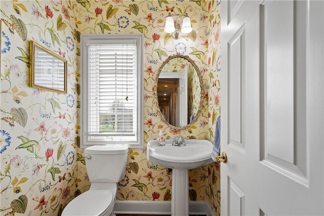 bathroom with toilet, a wealth of natural light, and wallpapered walls