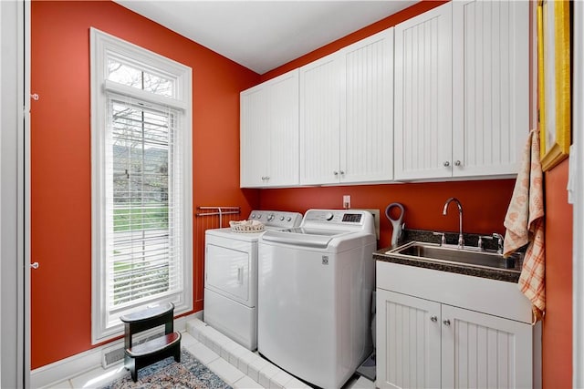 clothes washing area with light tile patterned floors, a sink, cabinet space, baseboards, and independent washer and dryer
