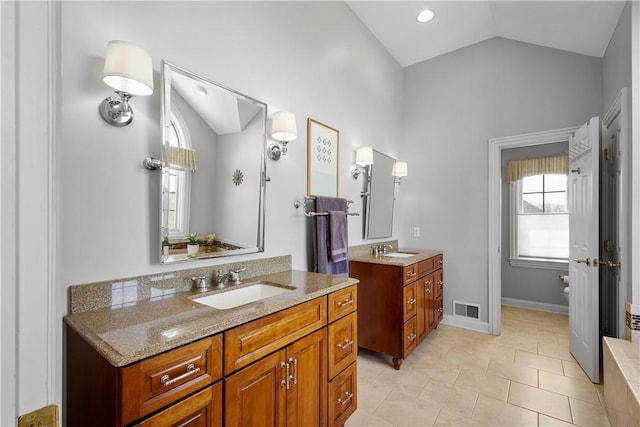 bathroom with visible vents, lofted ceiling, two vanities, and a sink