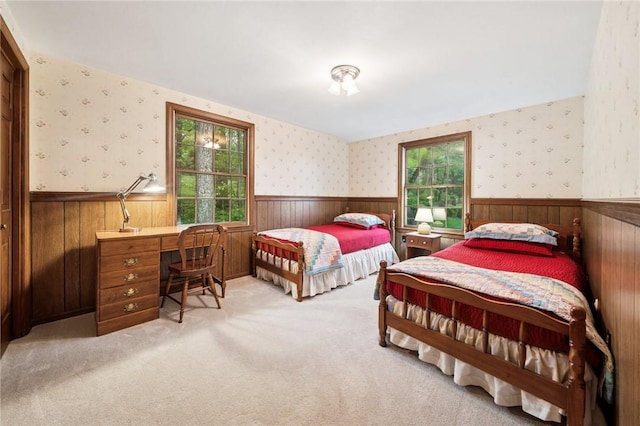 bedroom featuring light colored carpet, wood walls, and wainscoting