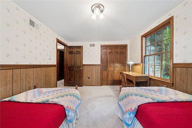 bedroom with wallpapered walls, visible vents, wainscoting, and wooden walls