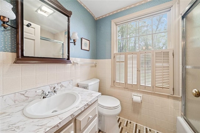 bathroom featuring tile walls, toilet, vanity, and wallpapered walls