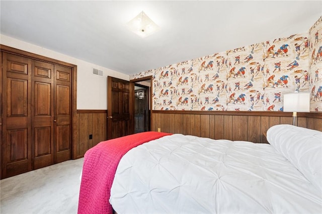 bedroom with wood walls, a closet, a wainscoted wall, visible vents, and carpet floors