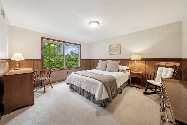 bedroom featuring light colored carpet, wooden walls, wainscoting, and visible vents