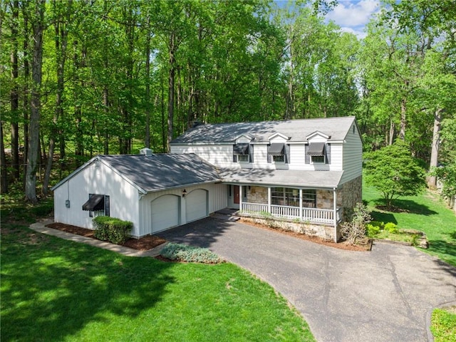 view of front of house featuring a front yard, an attached garage, stone siding, a porch, and aphalt driveway