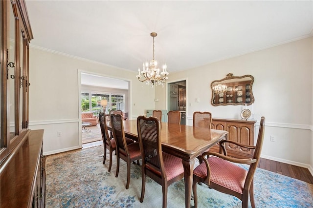 dining space featuring wood finished floors, baseboards, ornamental molding, and a notable chandelier
