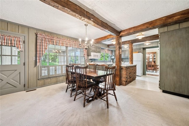 dining room with beam ceiling, a textured ceiling, visible vents, an inviting chandelier, and light carpet