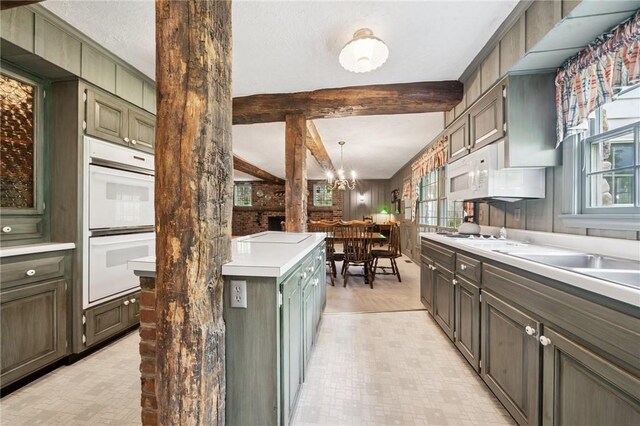 kitchen with white appliances, an inviting chandelier, beam ceiling, and plenty of natural light