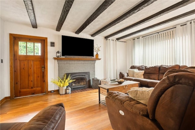 living area with a brick fireplace, beamed ceiling, baseboards, and wood finished floors