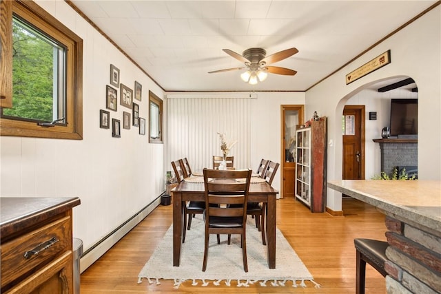 dining space featuring light wood-style flooring, a baseboard radiator, ceiling fan, and arched walkways
