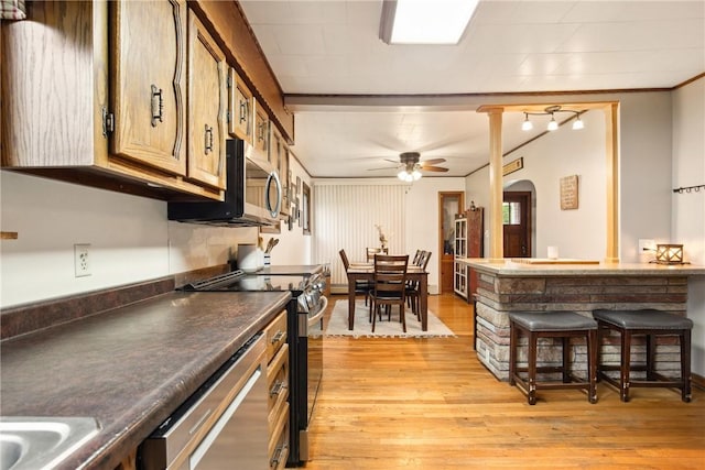 kitchen with light wood finished floors, stainless steel appliances, a ceiling fan, and arched walkways